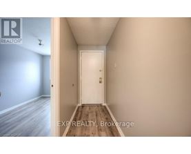 A hallway with a white door and a light switch on the wall.