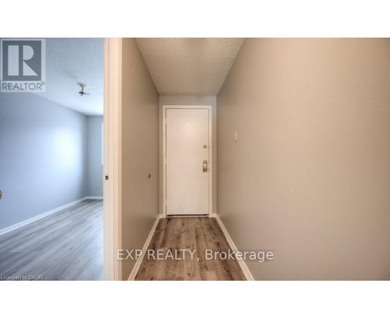 A hallway with a white door and a light switch on the wall.
