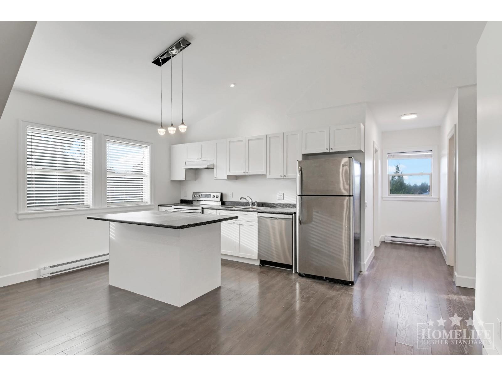 A modern kitchen with white cabinets and stainless steel appliances.