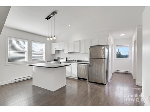 A modern kitchen with white cabinets and stainless steel appliances.
