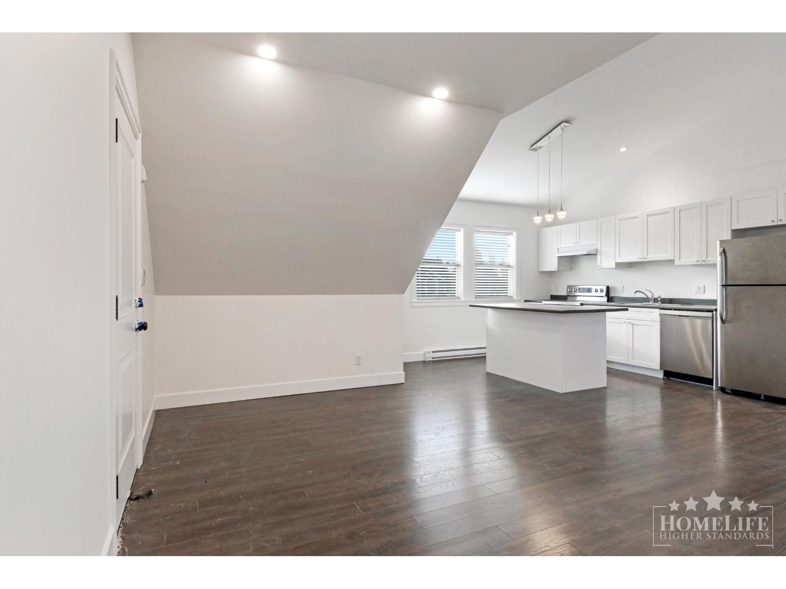 A spacious kitchen with white cabinets and stainless steel appliances.