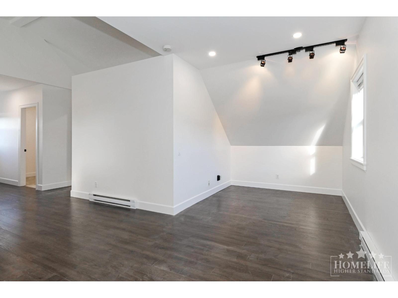 A large empty room with wooden floors and white walls.
