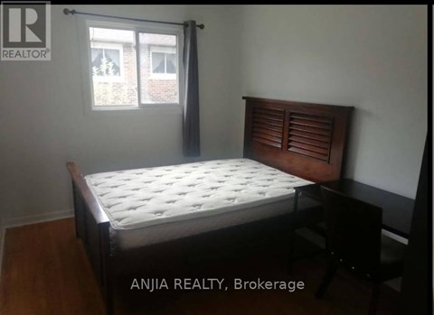 A bedroom with a bed, chair, and window.