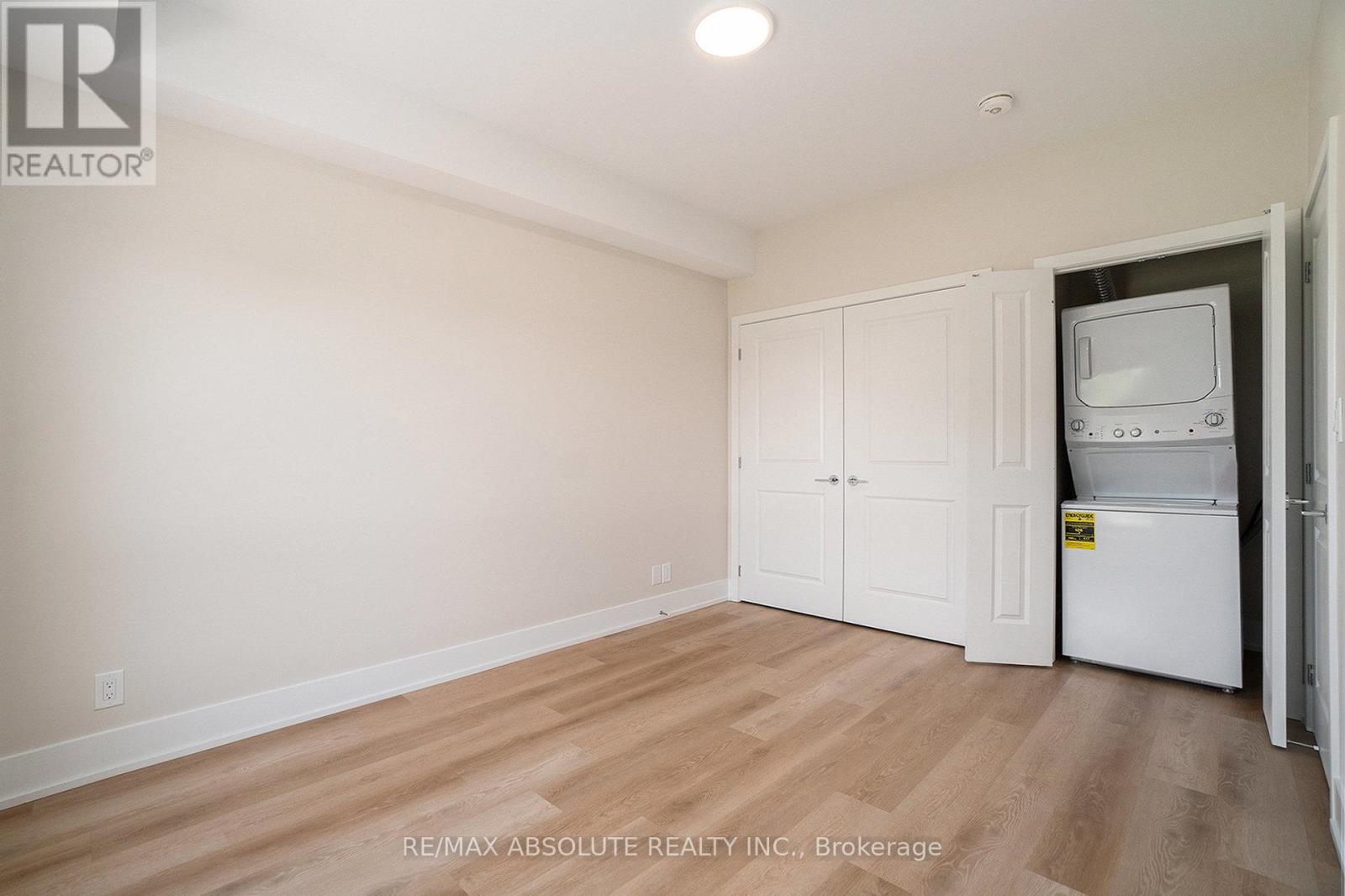 A white refrigerator is in a kitchen with wood floors and white cabinets.