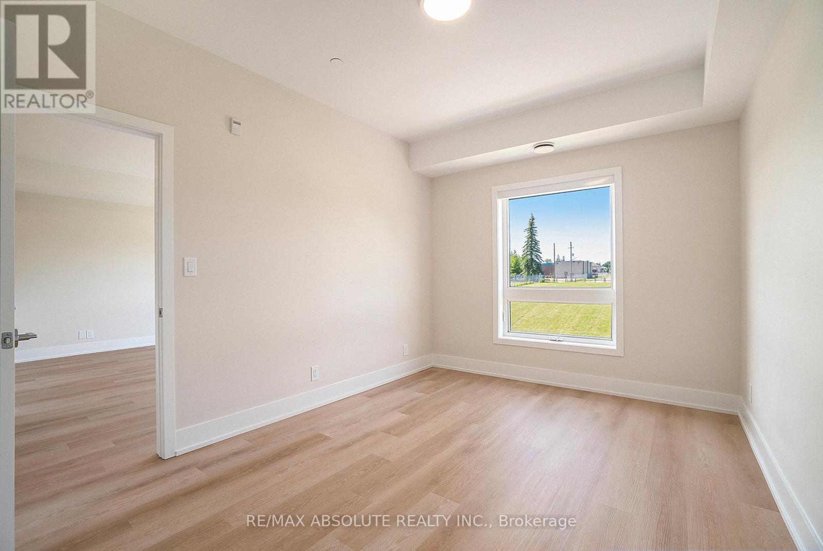 A room with a window showing a view of a building and trees outside.