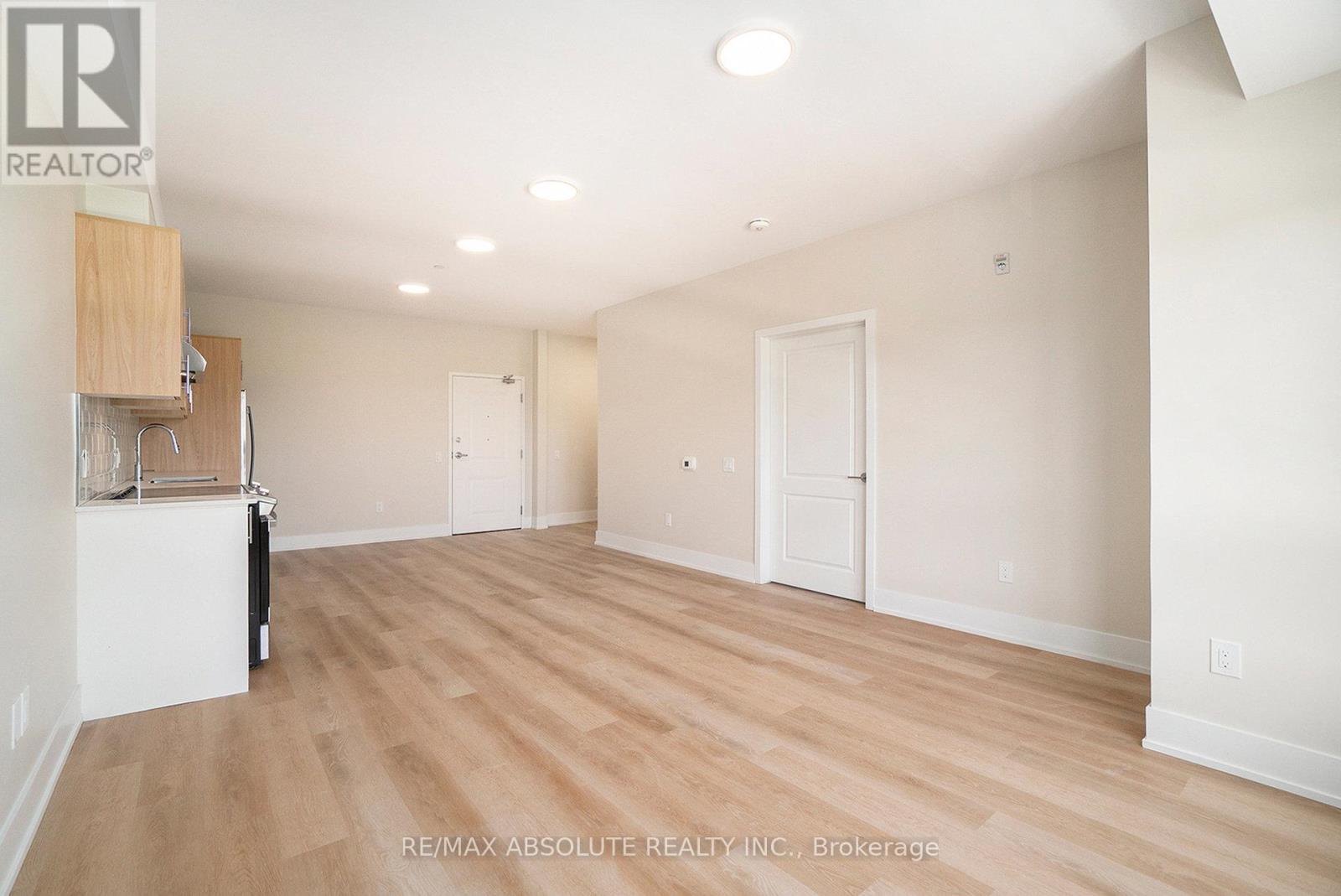 A spacious room with wooden flooring and white walls, with a cabinet and a chair in the corner.