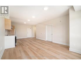 A spacious room with wooden flooring and white walls, with a cabinet and a chair in the corner.