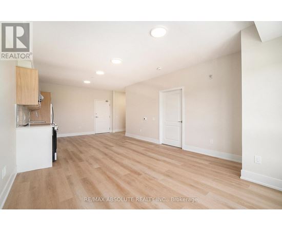A spacious room with wooden flooring and white walls, with a cabinet and a chair in the corner.