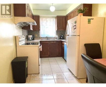 A kitchen with a white fridge and a black chair.