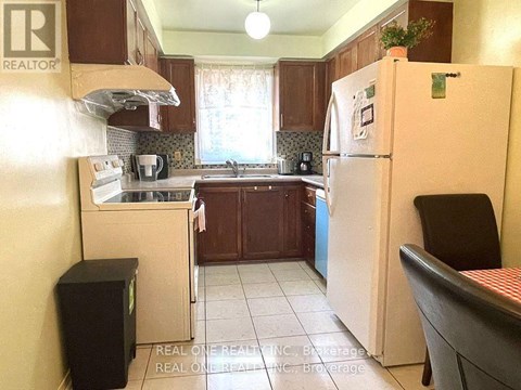 A kitchen with a white fridge and a black chair.
