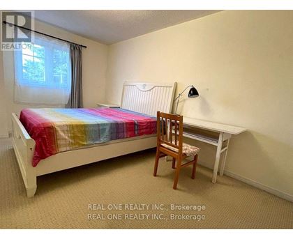 A bedroom with a bed, chair, and desk.