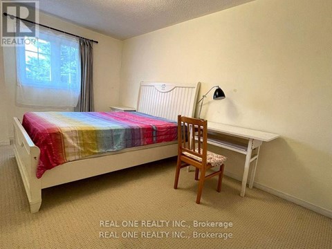 A bedroom with a bed, chair, and desk.