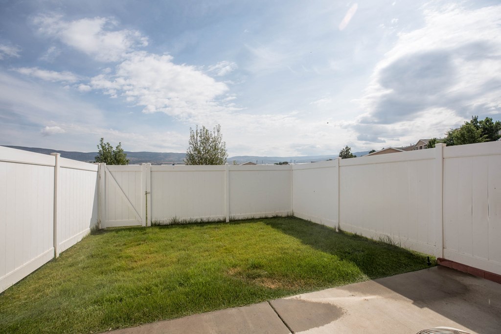 a backyard with a white fence and grass