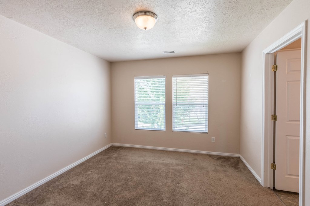 an empty room with two windows and a door