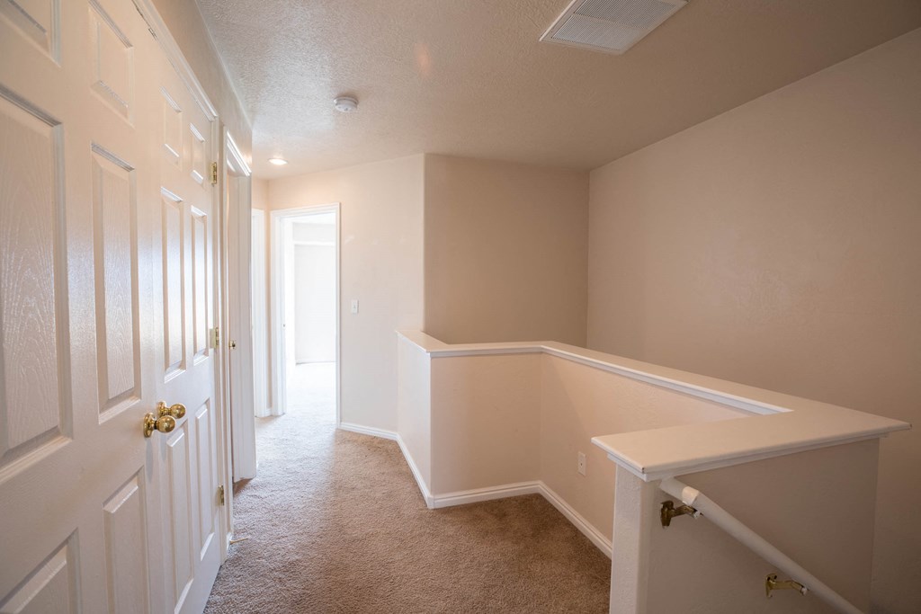 a empty room with a staircase and a hallway with white doors