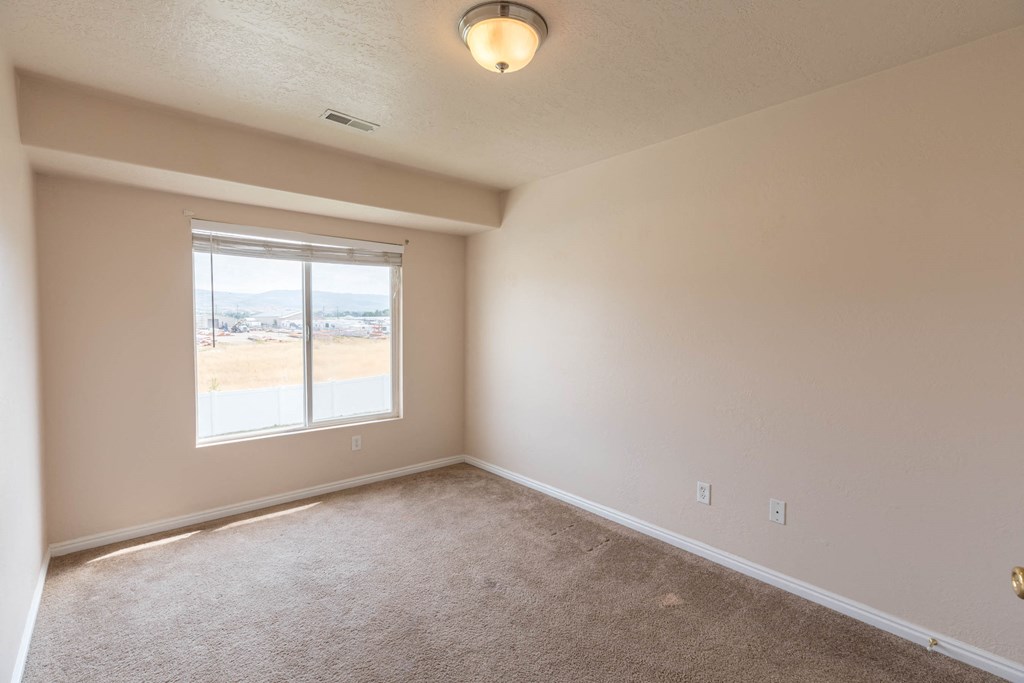 an empty living room with a window and carpet