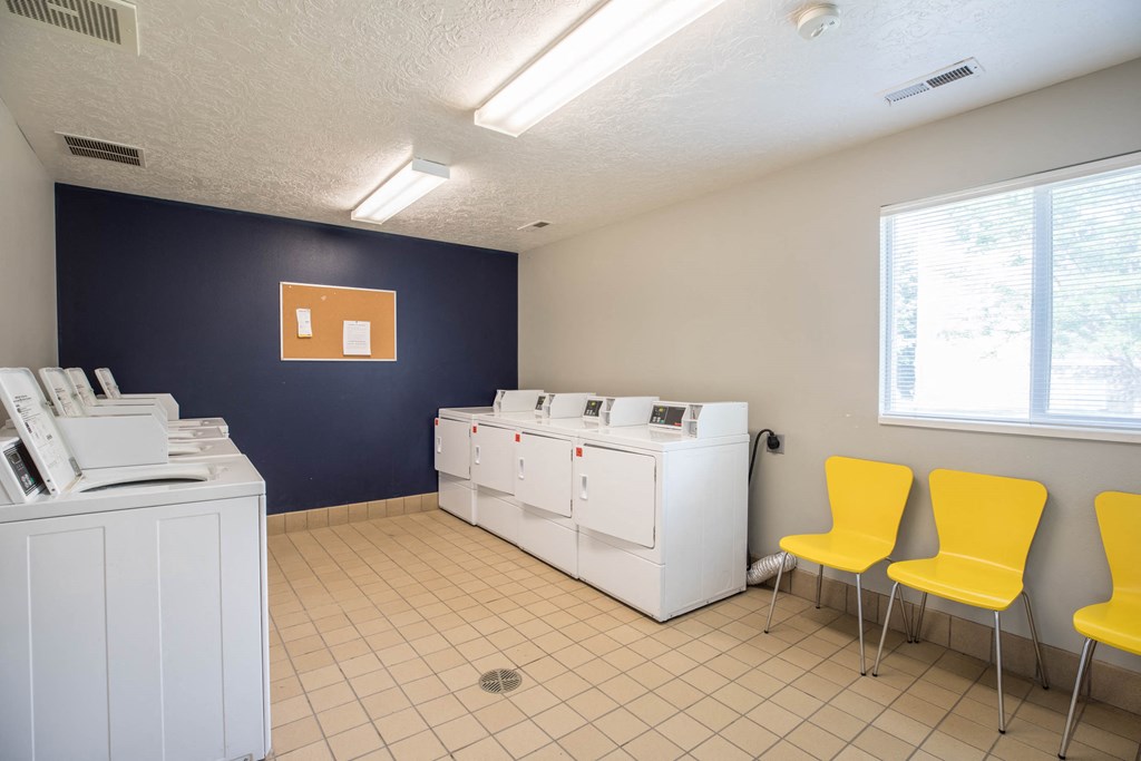 a laundry room with yellow chairs and washing machines