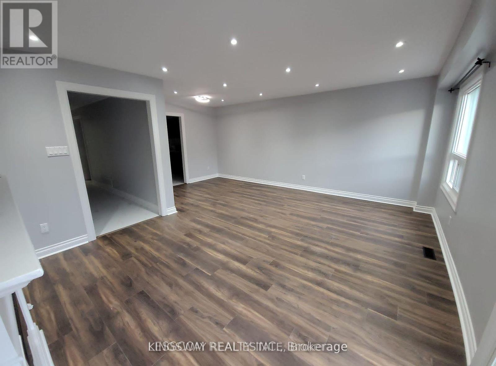 A room with wooden flooring and a large open space.