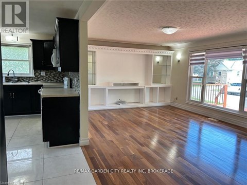 A kitchen with black cabinets and a wooden floor.