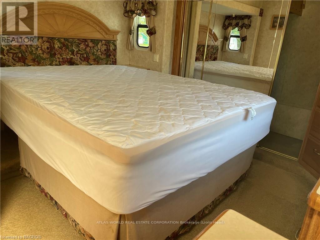 A bed with a white mattress in a room with floral wallpaper.