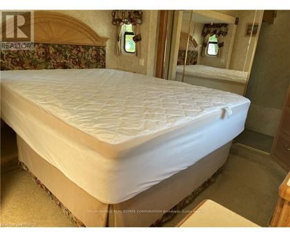 A bed with a white mattress in a room with floral wallpaper.