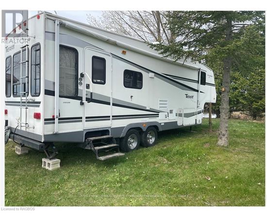 A white RV is parked in a grassy area.