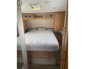 A bedroom with a bed, cupboard and a door.