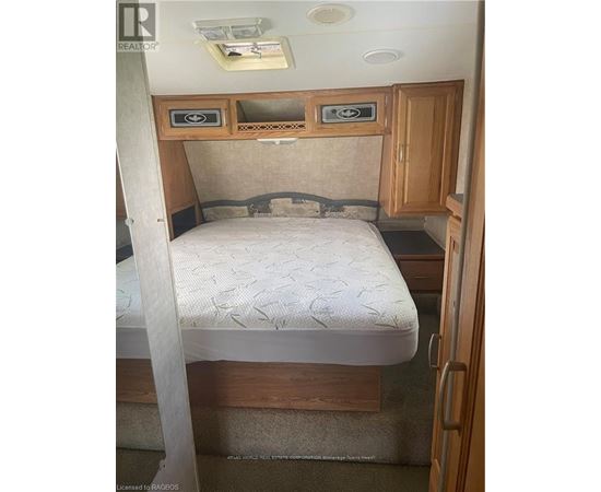 A bedroom with a bed, cupboard and a door.