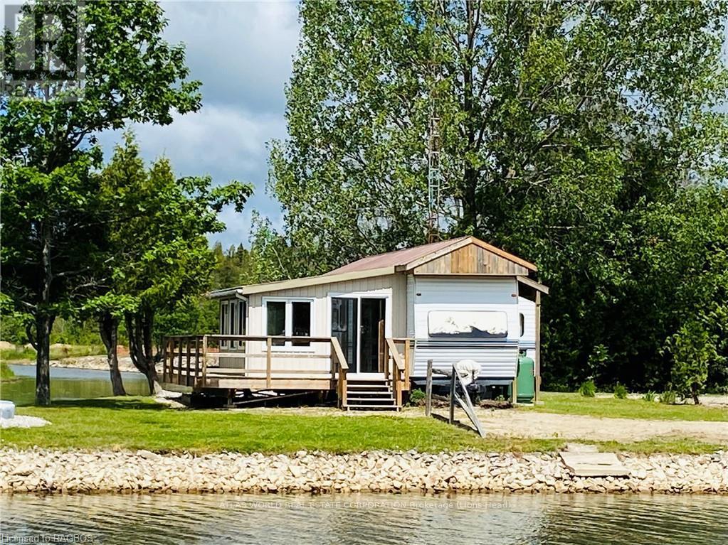 A houseboat is docked on a lake surrounded by trees.