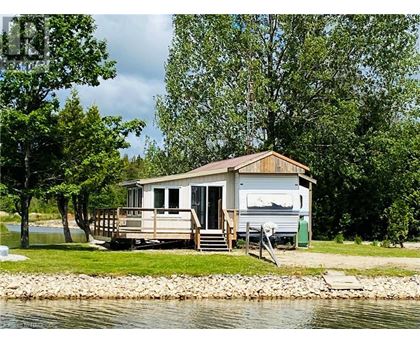 A houseboat is docked on a lake surrounded by trees.