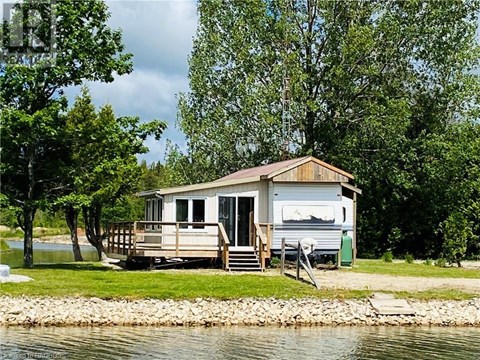 A houseboat is docked on a lake surrounded by trees.