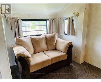 A beige couch with a window behind it in a room.