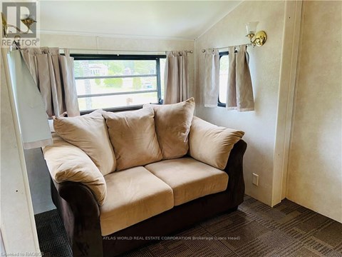 A beige couch with a window behind it in a room.
