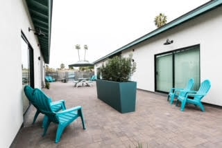 A patio with blue chairs and a green planter box.