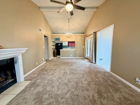A spacious living room with a fireplace and a ceiling fan.