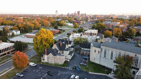 A parking lot is in the foreground of a town with a large building in the middle.