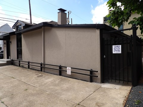 A small building with a black gate and a sign on it.