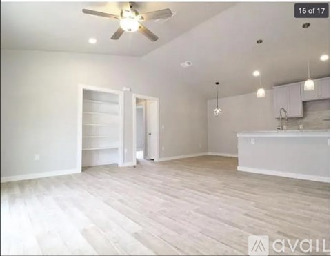 A spacious room with a ceiling fan and wooden flooring.