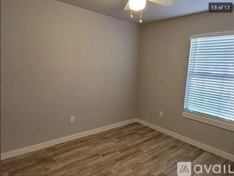 A room with wooden flooring and a window with blinds.