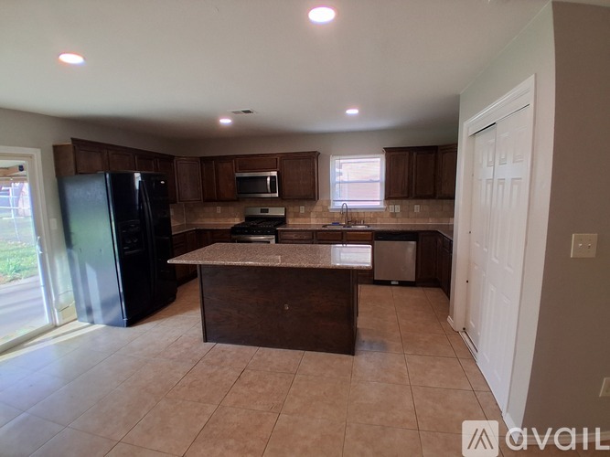 A kitchen with brown cabinets and a black refrigerator.