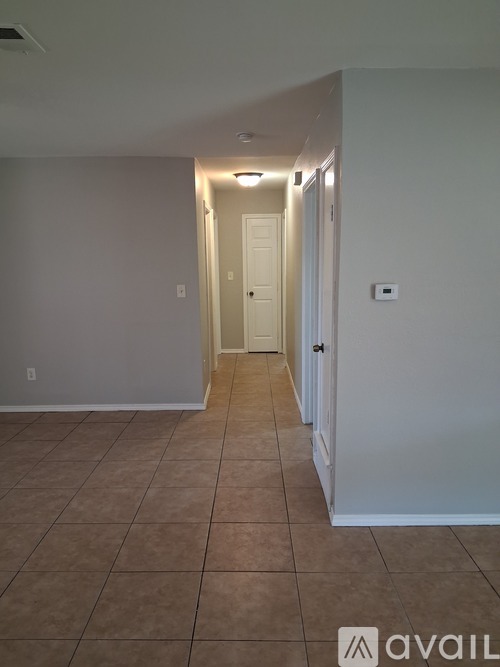 A hallway with tiled flooring and white walls.