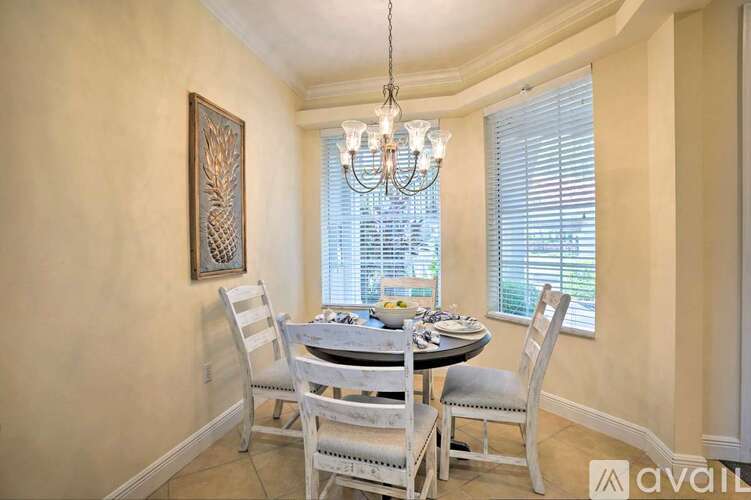 A dining room with a table set for four and a chandelier hanging from the ceiling.