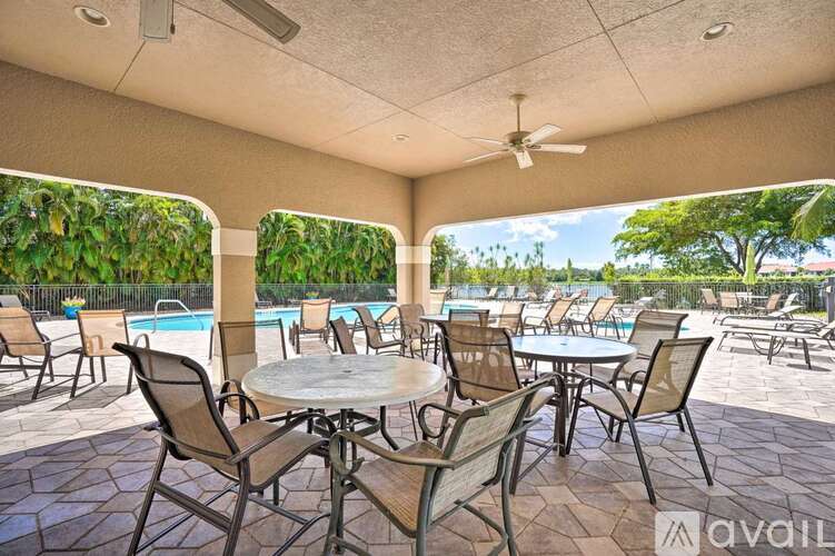 A patio with a table and chairs overlooking a pool.