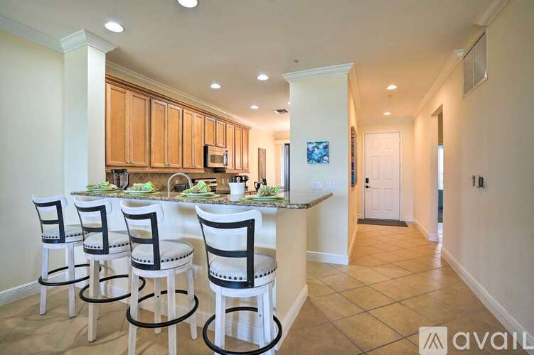 A kitchen with white chairs and a counter.