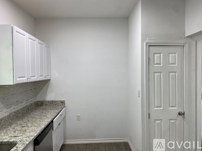 A kitchen with white cabinets and a granite countertop.