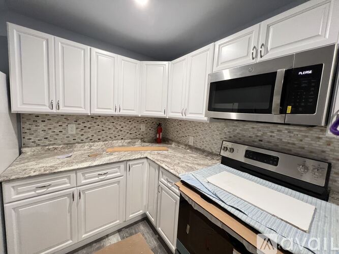 A kitchen with white cabinets and a microwave above the stove.