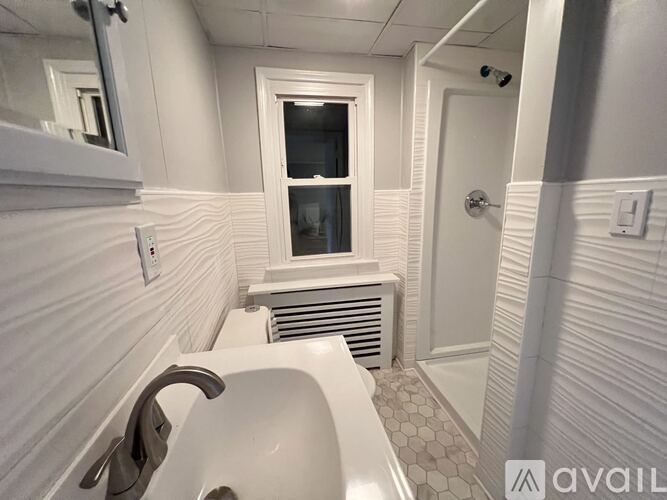 A white bathroom with a tub and a window.