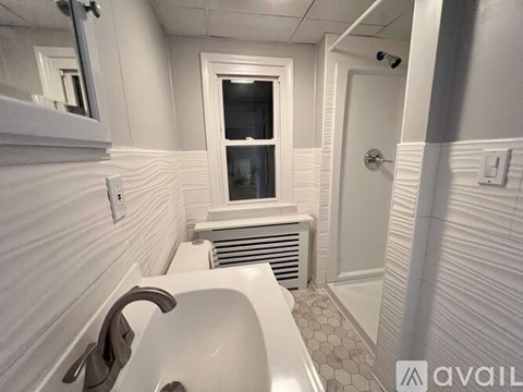 A white bathroom with a tub and a window.