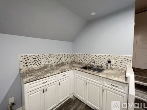 A kitchen with white cabinets and a marble backsplash.