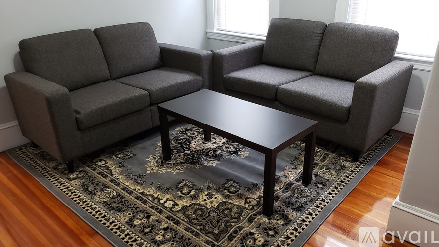 A grey couch and a coffee table are on a patterned rug in a room.